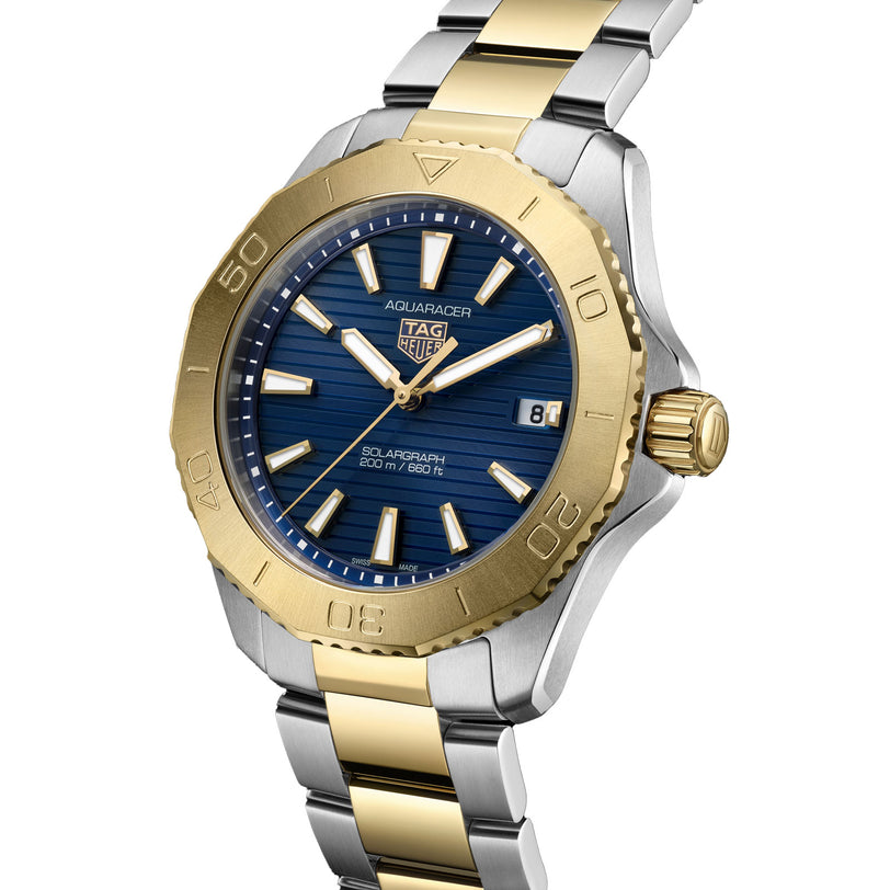 The TAG Heuer Aquaracer Professional 200 Solargraph features a blue dial, gold bezel, two-tone gold and silver metal bracelet, and a date display at 3 o’clock.