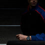 A person in a dark jacket with blue and red stripes is wearing a TAG Heuer Formula 1 Chronograph on their wrist.