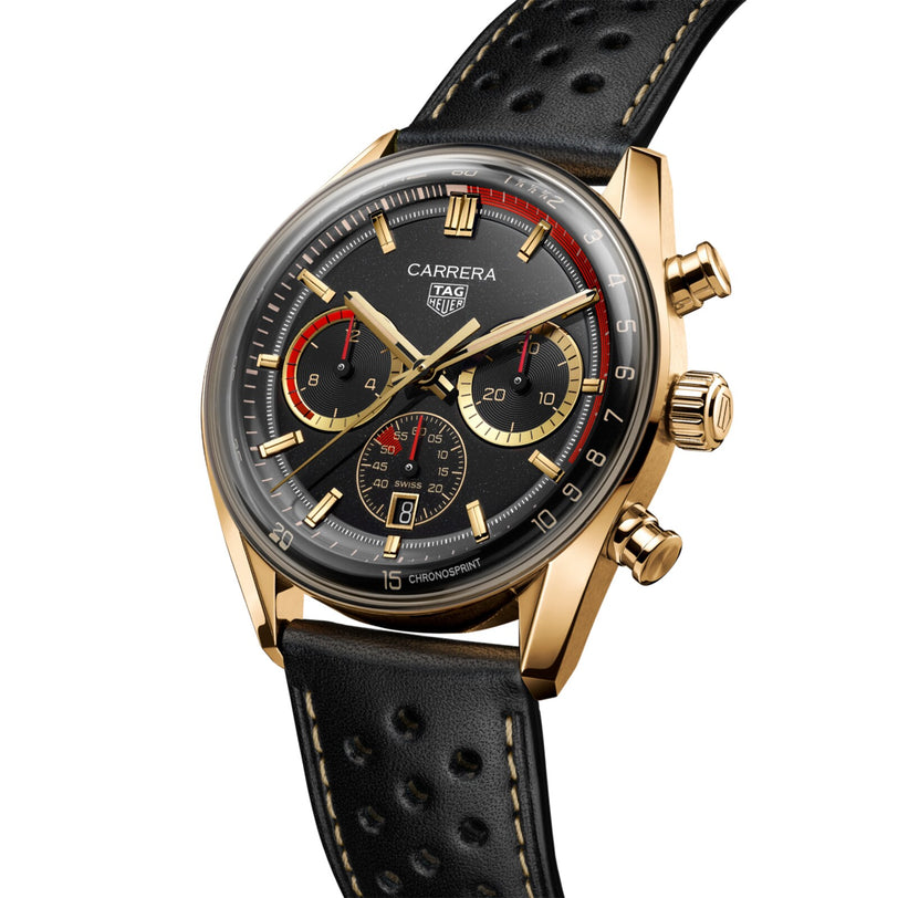 TAG Heuer Carrera Chronosprint x Porsche Rallye chronograph watch with a gold case, black dial, and leather strap, displayed at an angle.