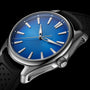 A close-up of the H. Moser & Cie Pioneer Centre Seconds, an automatic watch featuring an Arctic Blue fumé dial with silver markers and hands, plus a black perforated strap, set against a black background.