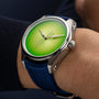 The H. Moser & Cie Pioneer Centre Seconds Concept Citrus Green wristwatch features a striking green gradient dial and blue strap on the wearer’s wrist.