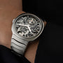 A close-up of the H. Moser & Cie Streamliner Tourbillon Skeleton watch, its visible movement displayed on a left wrist with a black sleeve, capturing minimalist style.