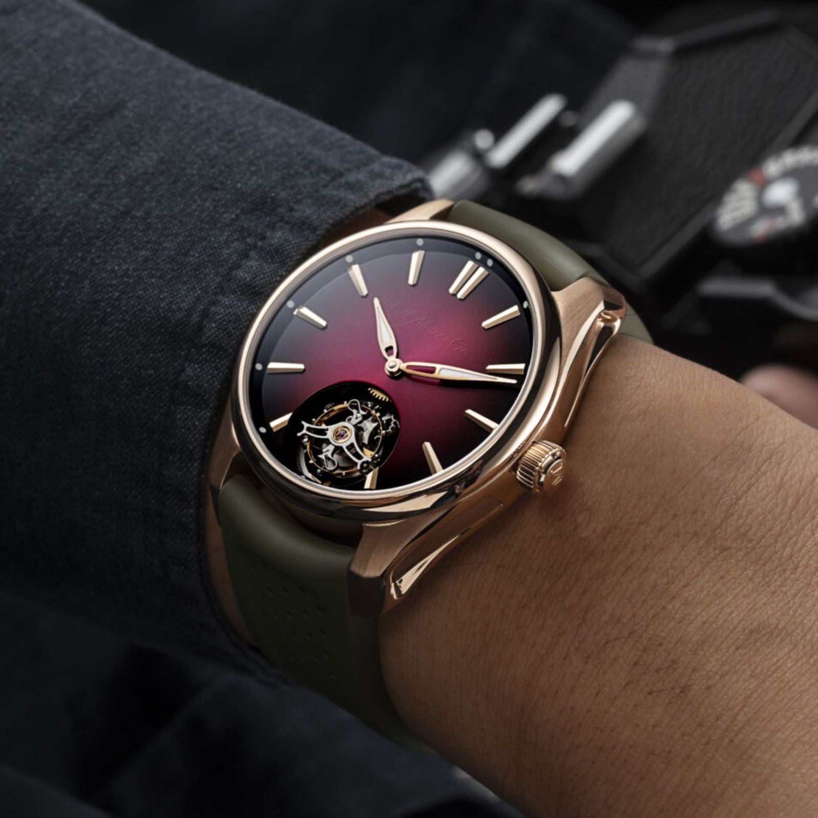 The H. Moser & Cie Pioneer Tourbillon Burgundy, featuring a red gradient dial and visible tourbillon, is worn on a persons wrist.