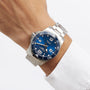 A close-up of a wrist wearing the Longines HydroConquest, a water-resistant stainless steel diving watch with a blue dial, white numerals, and date display, paired with a white dress shirt.