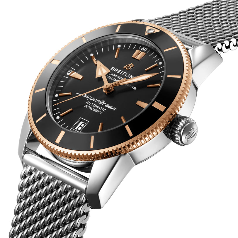 Close-up of the Breitling Superocean Heritage B20 Automatic 42 featuring a black dial with gold accents, date window, and stainless steel mesh bracelet, powered by the reliable Breitling B20 movement.
