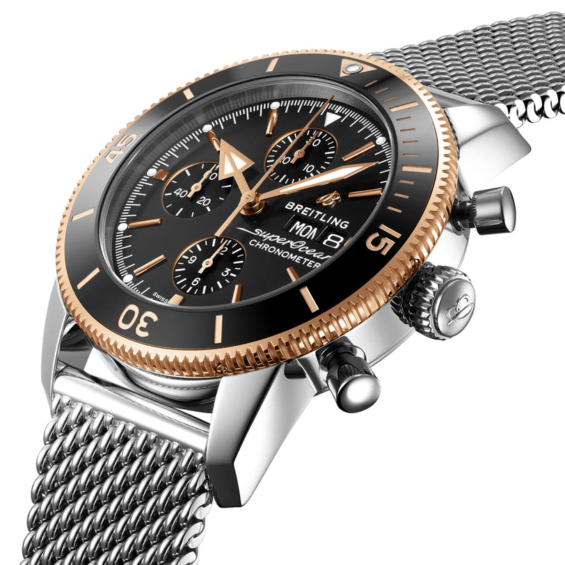 Close-up of the Breitling Superocean Heritage B20 Automatic 44, featuring a black dial, gold bezel, three subdials, and a 44mm stainless steel mesh bracelet; this chronometer offers exceptional water resistance.