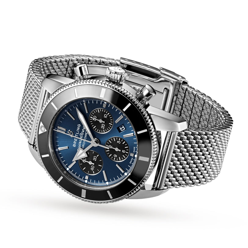 A Breitling Superocean Heritage B01 Chronograph 44 in stainless steel, featuring a blue dial with three subdials, date window, mesh bracelet, and Breitling 01 calibre, is shown at an angle on a white background.