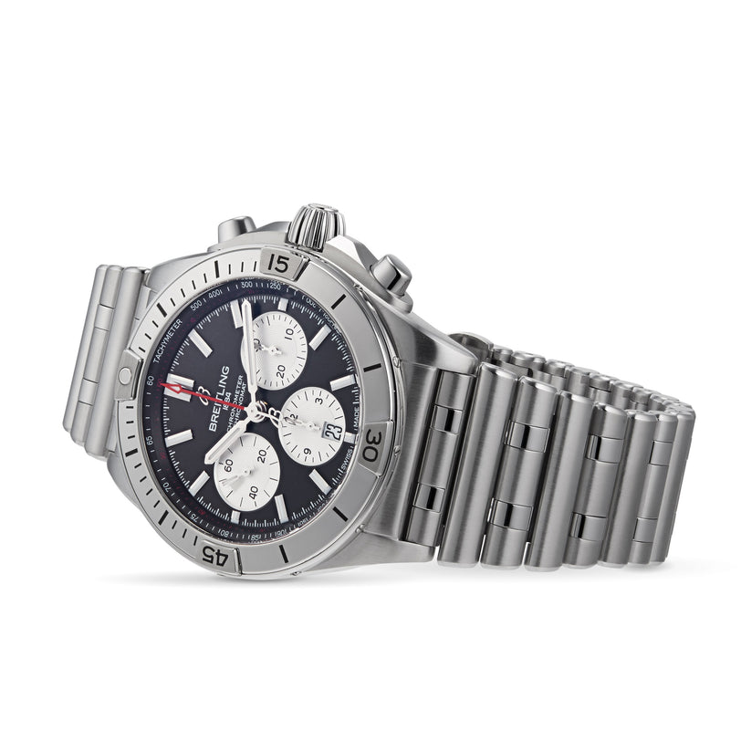 Shown at an angle is a Breitling Chronomat B01 42 watch featuring a stainless steel case, black dial with three subdials, and a metal link bracelet.