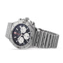 Shown at an angle is a Breitling Chronomat B01 42 watch featuring a stainless steel case, black dial with three subdials, and a metal link bracelet.