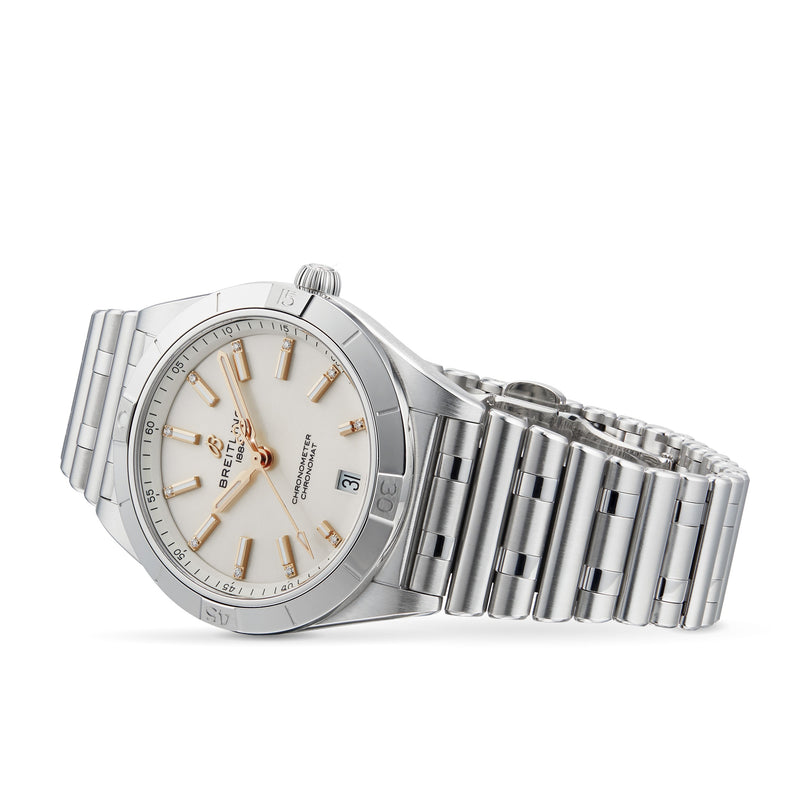 A Breitling Chronomat Automatic 36 wristwatch with a silver Rouleaux bracelet, white dial, gold hour markers, and date display is shown angled on its side.