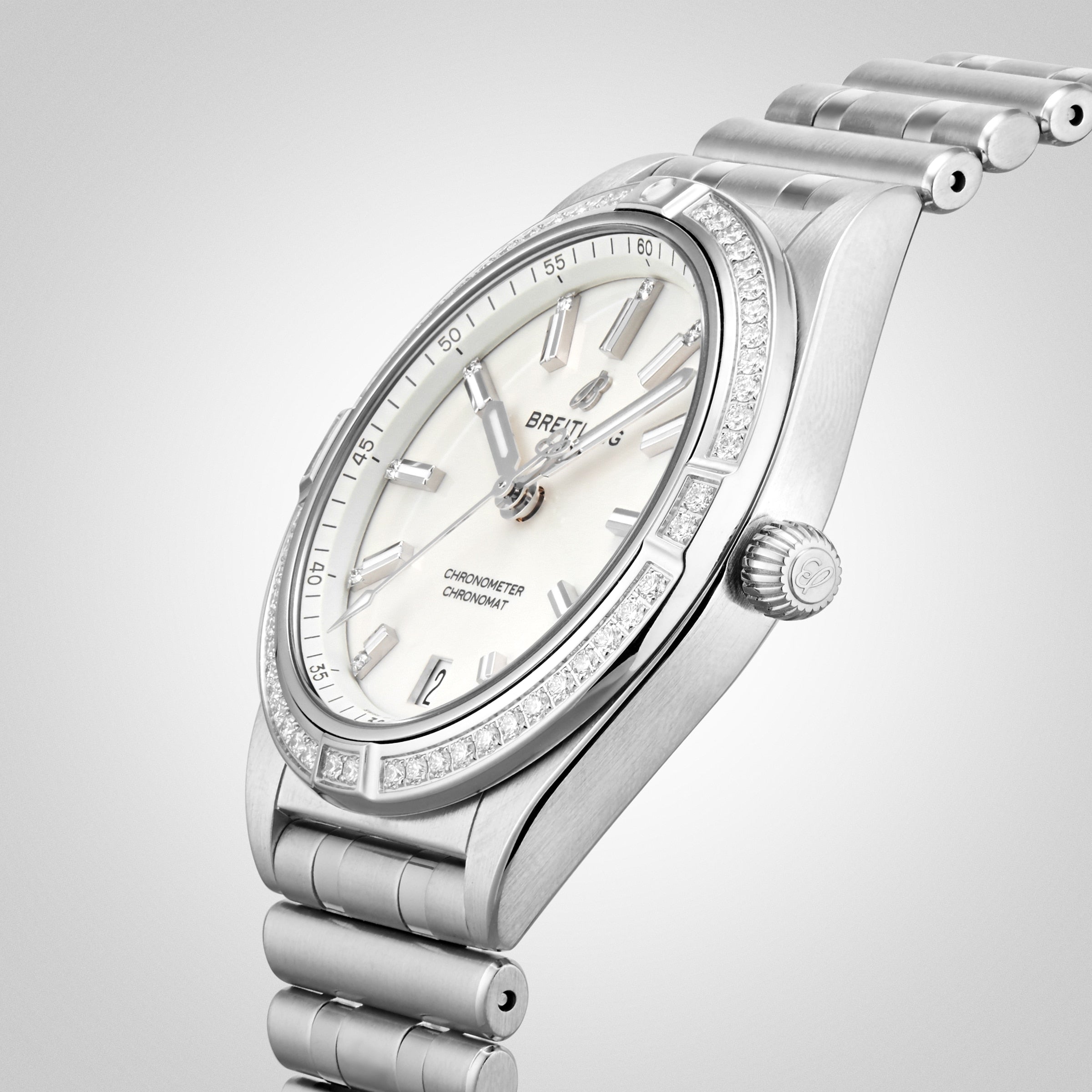 A Breitling Chronomat Automatic 36 wristwatch with a white dial, diamond-set bezel, and Rouleaux bracelet is displayed at an angle on a light background.