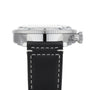 Side view of the Breitling Super AVI B04 Chronograph GMT 46 Tribute To Vought F4U, featuring a black leather strap with white stitching, silver case, ridged bezel, and crown on the right side.