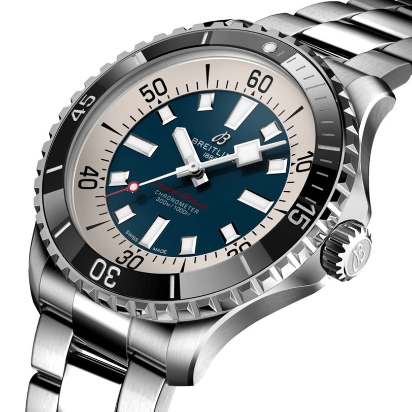 A close-up angled view of the Breitling Superocean Automatic 44, a stainless steel dive watch with blue and cream dial, bold markers, rotating bezel, metal bracelet, and automatic movement.