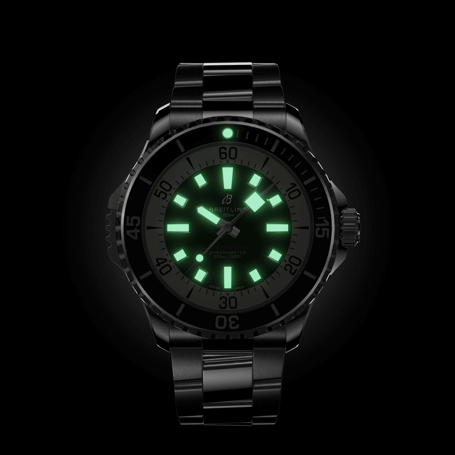 The Breitling Superocean Automatic 46 is a black wristwatch with a metal band, glowing green hour markers and hands on a dark dial, inspired by the iconic 1960s Slow Motion design.