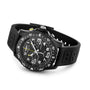 A black Breitling Endurance Pro 44 chronograph wristwatch with large numerals, subdials, a rotating bezel made from lightweight Breitlight®, and a rubber strap is displayed on a flat surface.