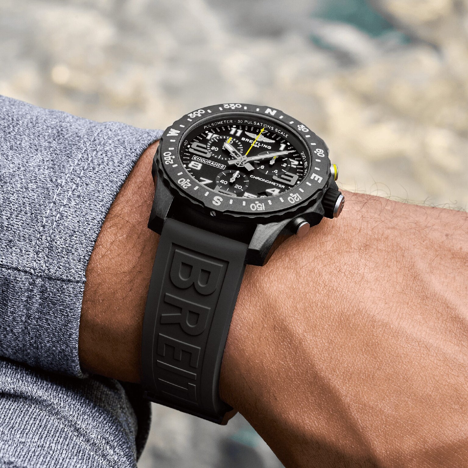 A person wearing a Breitling Endurance Pro 44 wristwatch with a black textured rubber strap and a compass bezel.