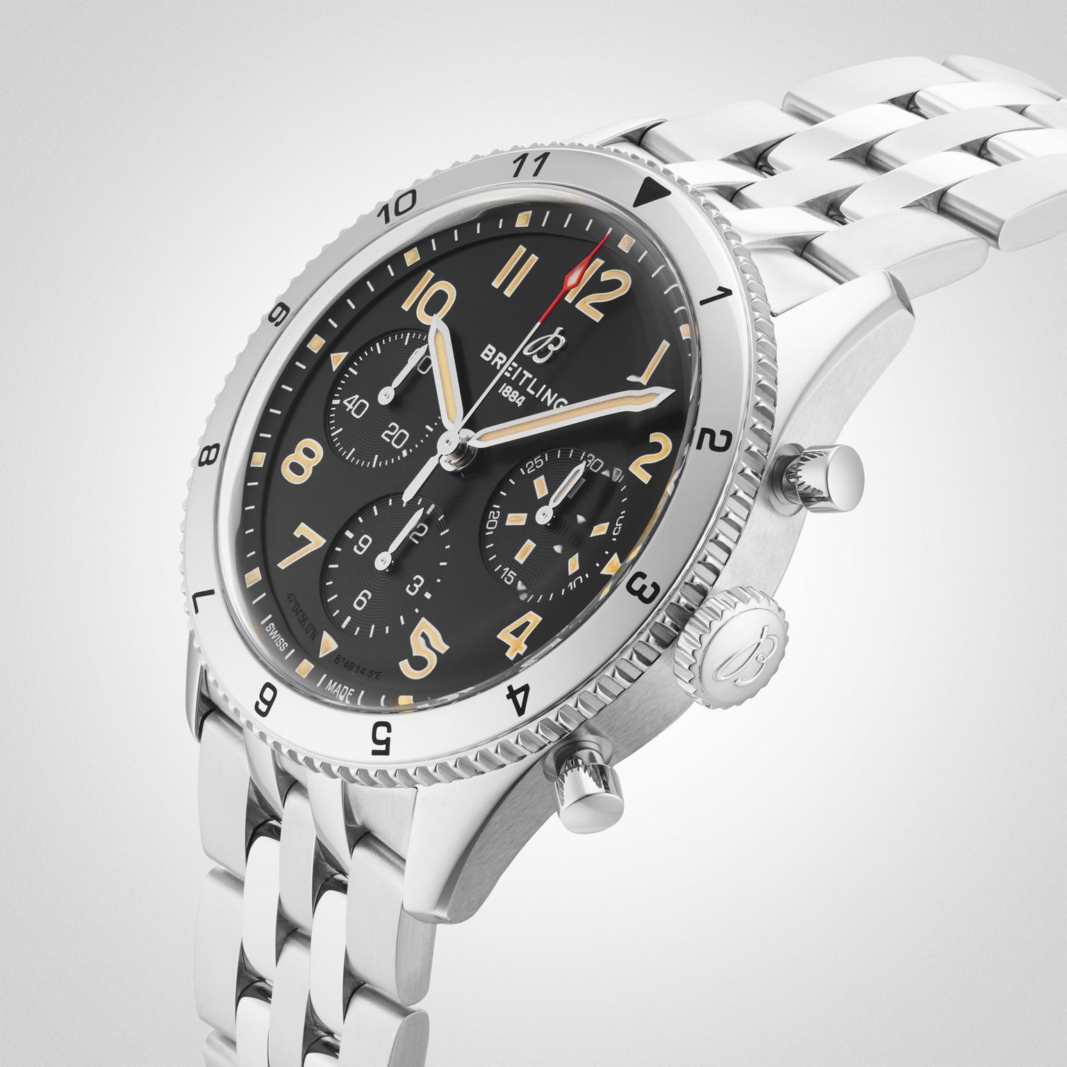 The Breitling Classic AVI Chronograph 42 P-51 Mustang, a stainless steel pilot’s watch with a black dial, Arabic numerals, three subdials, and metal link bracelet, is shown on a light background, reflecting its classic aviation heritage.