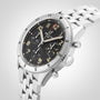 The Breitling Classic AVI Chronograph 42 P-51 Mustang, a stainless steel pilot’s watch with a black dial, Arabic numerals, three subdials, and metal link bracelet, is shown on a light background, reflecting its classic aviation heritage.