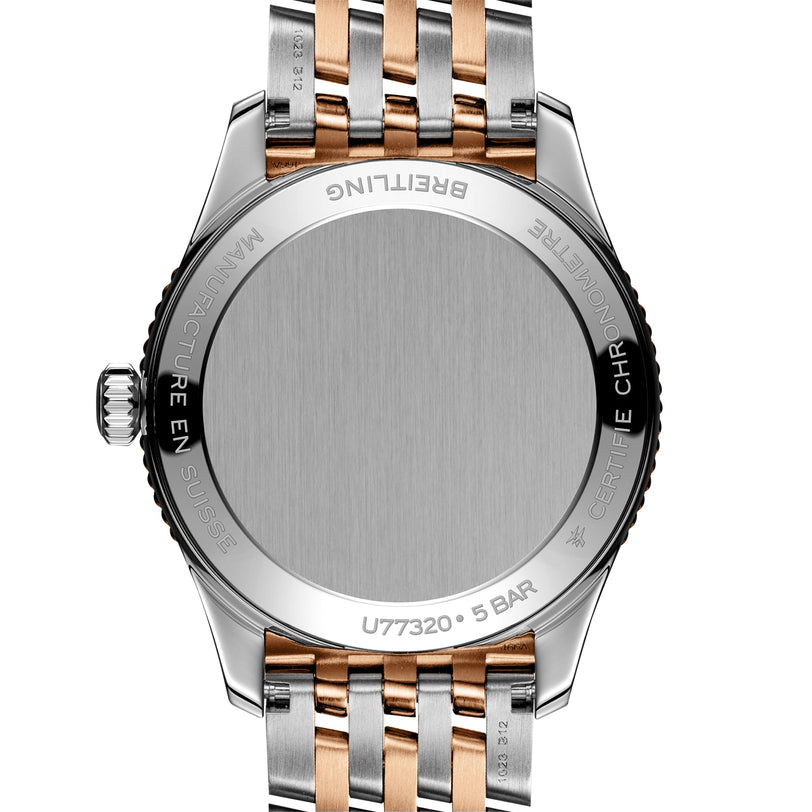 Close-up view of the back of a Breitling Navitimer 32 wristwatch featuring a silver and 18K red gold metal bracelet and engraved detailing around the case edge.