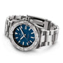The Breitling Avenger Automatic 42 is a stainless steel wristwatch with a blue dial, date display, silver hour markers, and metal link bracelet. Featuring a military-inspired design, its pictured at an angle on a white background.