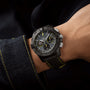 A person sports the Breitling Avenger B01 Chronograph 44 Night Mission Bloodhounds, a black watch with yellow stitching, paired with a dark outfit featuring matching cuffs—evoking jet pilot precision.