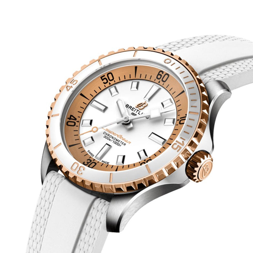 The Breitling Superocean Automatic 36 is a luxury dive watch with a white strap and dial, gold bezel, silver case, and gold/white indices and hands. It offers precision timekeeping with its automatic movement.
