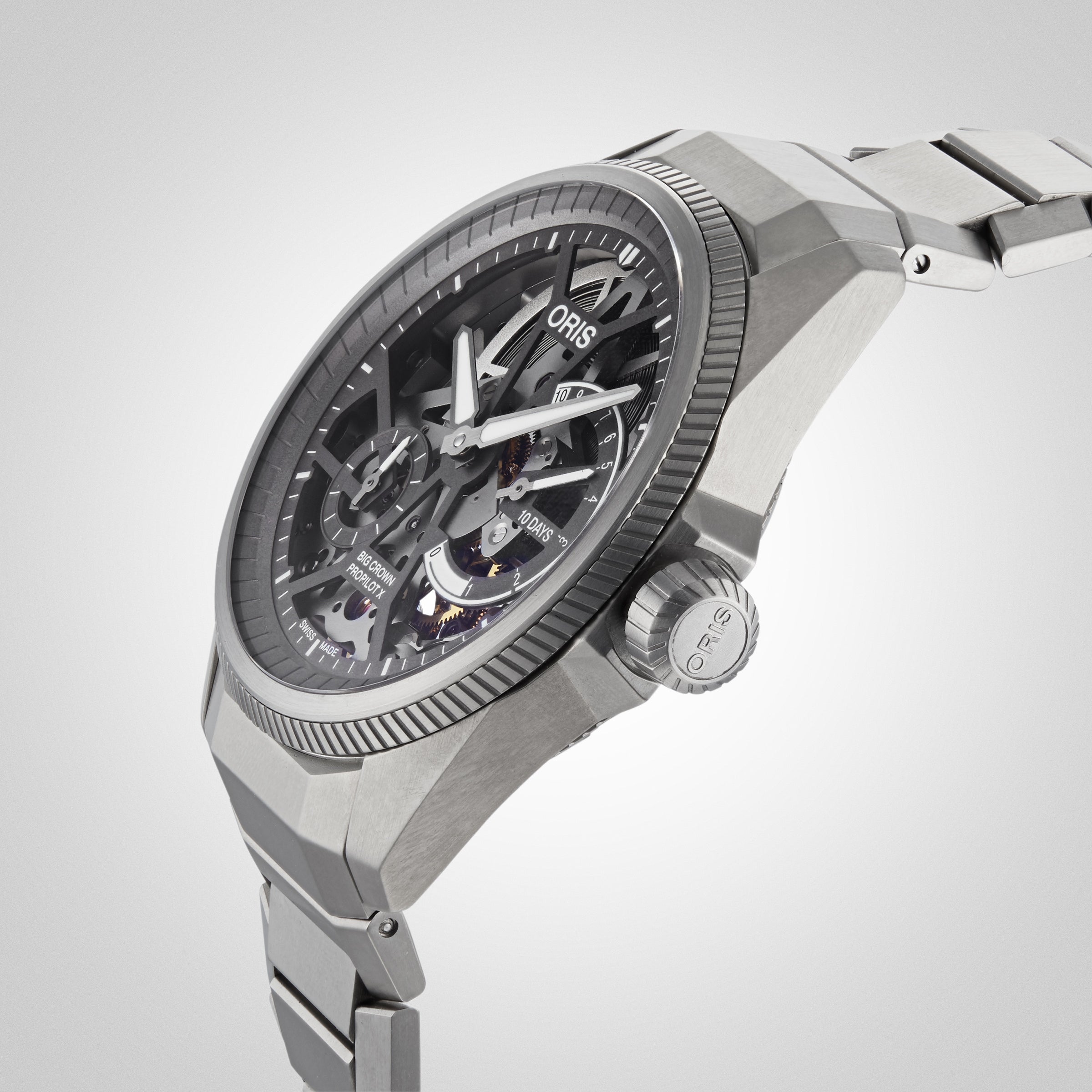 A close-up of the Oris ProPilot X Calibre 115 highlights its skeleton dial, stainless steel case and bracelet, exposed Calibre 115 movement, and labeled crown—an authentic Swiss Made mechanical watch.