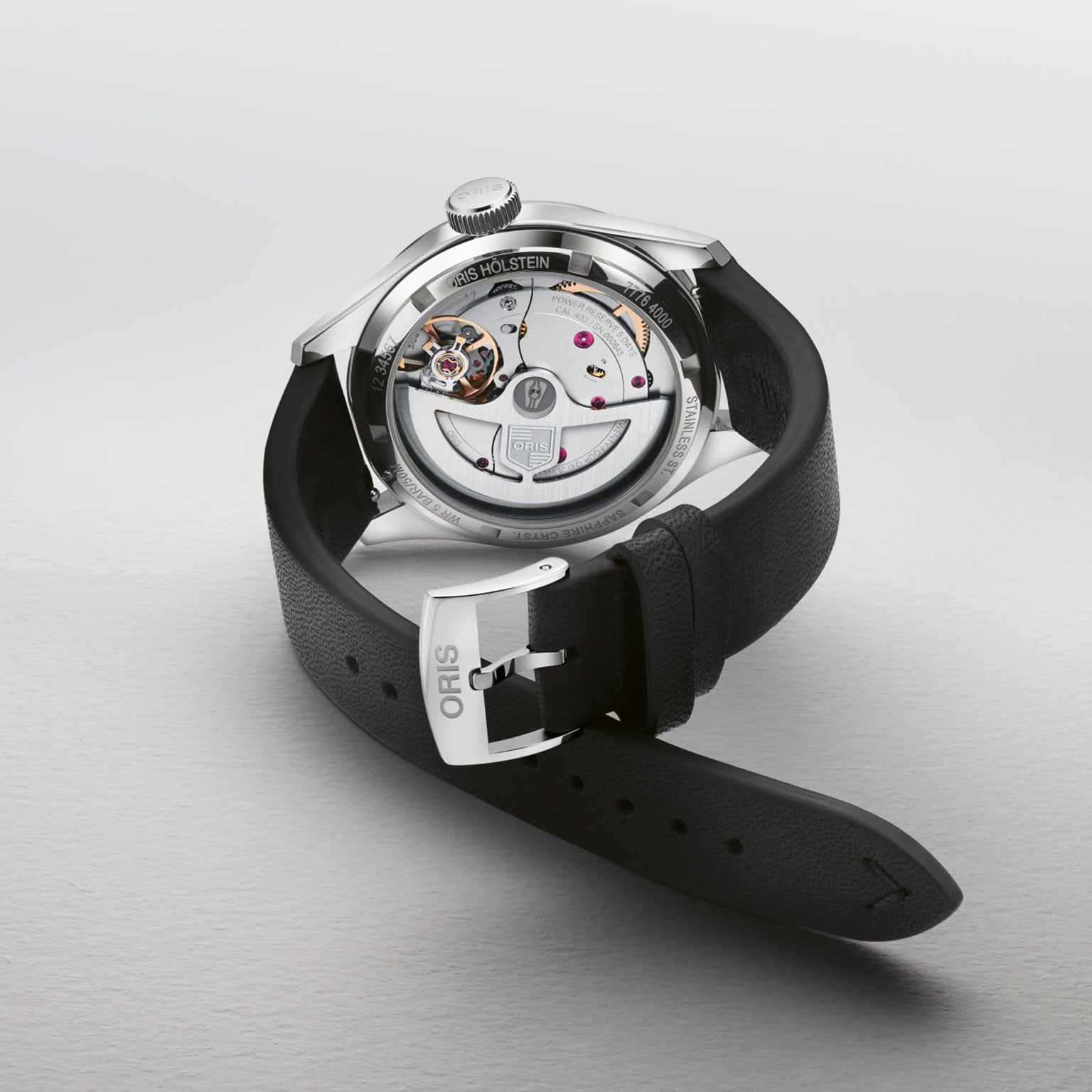 The Oris Big Crown Pointer Date Calibre 403 wristwatch with a black leather strap is displayed face down, revealing its intricate movement and inner workings, with Oris engraved on the buckle.
