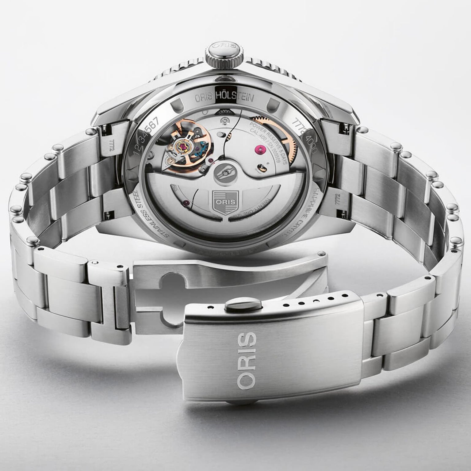 The Oris Divers Sixty‑Five 12H Calibre 400 features a silver-tone metal bracelet and an open case back that displays its automatic movement.