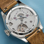 Close-up of the Oris Big Crown Pointer Date Calibre 473’s open case back, showcasing its hand-wound movement and intricate mechanics, complemented by a brown leather strap.
