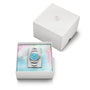The Oris Divers Sixty‑Five Cotton Candy, a silver wristwatch with a blue face, is displayed in a white box with pastel lining, next to its lid.
