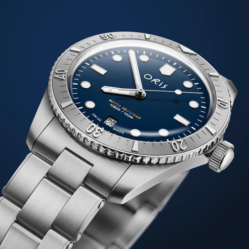 The Oris LFP Limited Edition is a stainless steel wristwatch with a blue dial, rotating bezel, and metal bracelet, shown against a dark blue background—created to celebrate the Ligue de Football Professionnel.