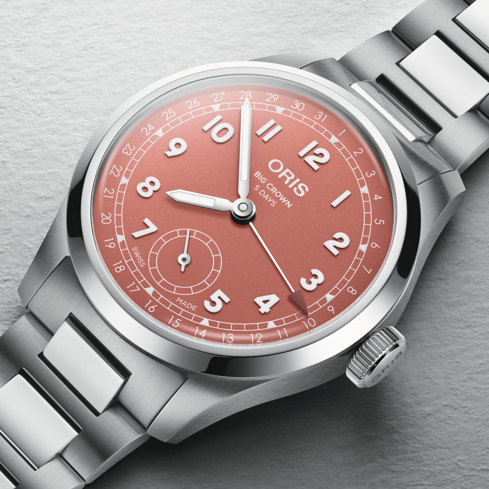 A stainless steel Oris Big Crown Pointer Date Calibre 403 wristwatch with a metal band, terracotta dial featuring Arabic numerals, a date ring, and the brand name on the face.