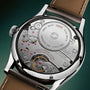 Close-up of a mechanical watch with visible brand name on a dark green background