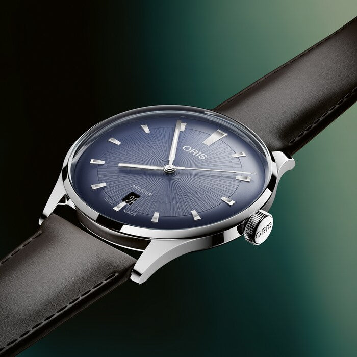 Oris watch with black leather strap and blue dial on a gradient green background