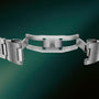 Stainless steel watch bracelet with curved links, fold-over clasp, and green rubber strap inlay, shown from above.