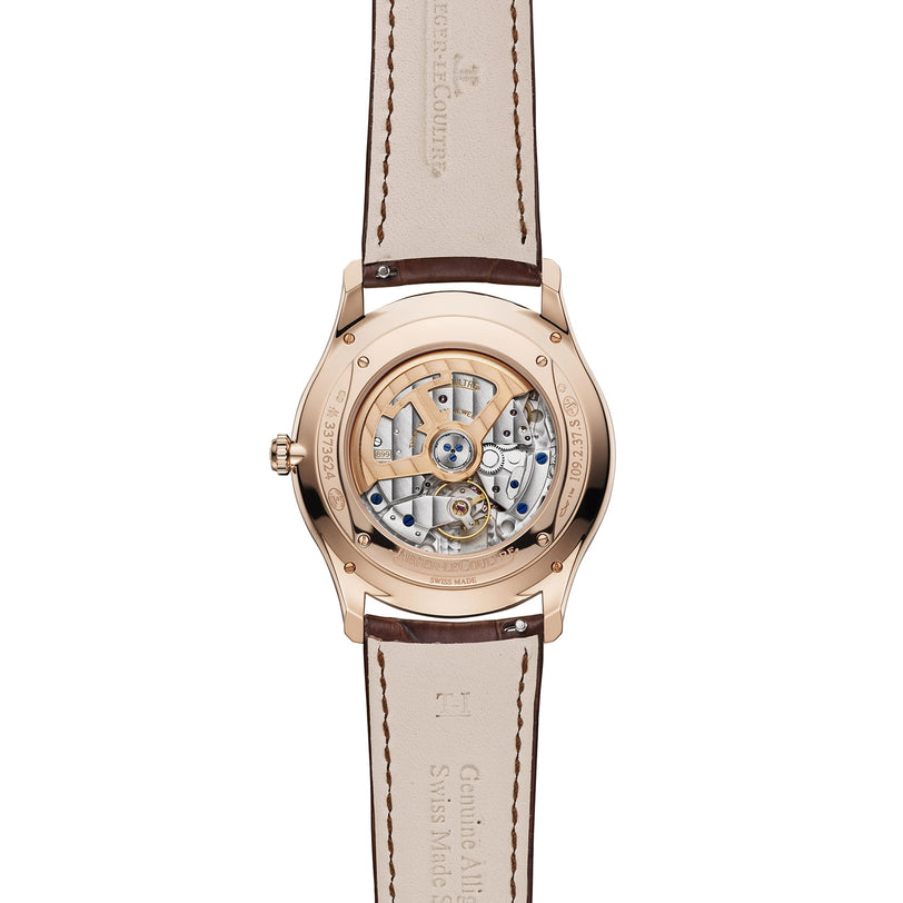 Back view of the Jaeger-LeCoultre Master Ultra Thin Date in pink gold, featuring a transparent case that reveals the Caliber 899 and a brown leather strap with "Jaeger-LeCoultre" engraved on both case and strap.