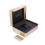 An open Jaeger-LeCoultre watch box in gold and black reveals a cushioned slot for the Master Ultra Thin Date. The brand’s logo appears inside the lid, with a card featuring gold accents placed next to the box.