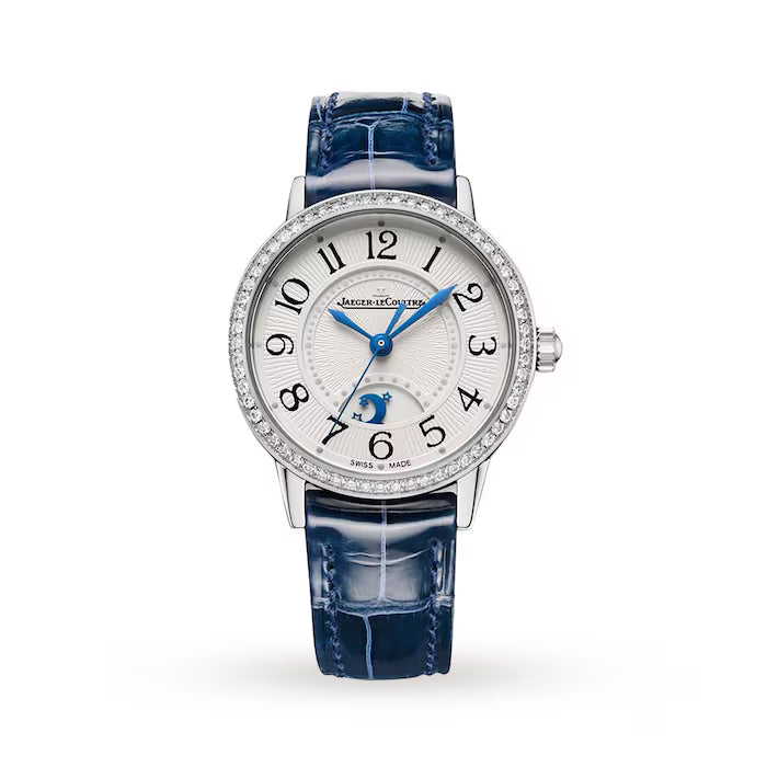The Jaeger-LeCoultre Rendez-Vous Night & Day is a luxury Swiss watch with a blue leather strap, diamond bezel, silver dial with black Arabic numerals, blue hands, and a moon phase display above 6 o’clock.