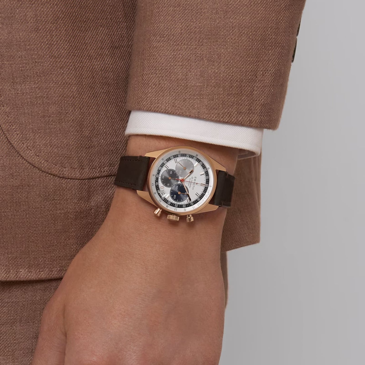 A man in a brown suit and white shirt with the Chronomaster EP Original on wrist