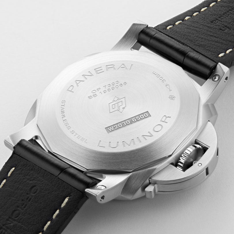 Close-up of the back of a Panerai Luminor Marina wristwatch, showing engraved details on the stainless steel case, black leather strap with white stitching, and a partially visible crown guard.