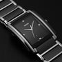 A close-up of the Rado Integral Diamonds watch showcases its rectangular black dial with silver hour markers, diamond accents, and a metal bracelet. Featuring high-tech ceramic and quartz movement, this timepiece stands out against a dark background.