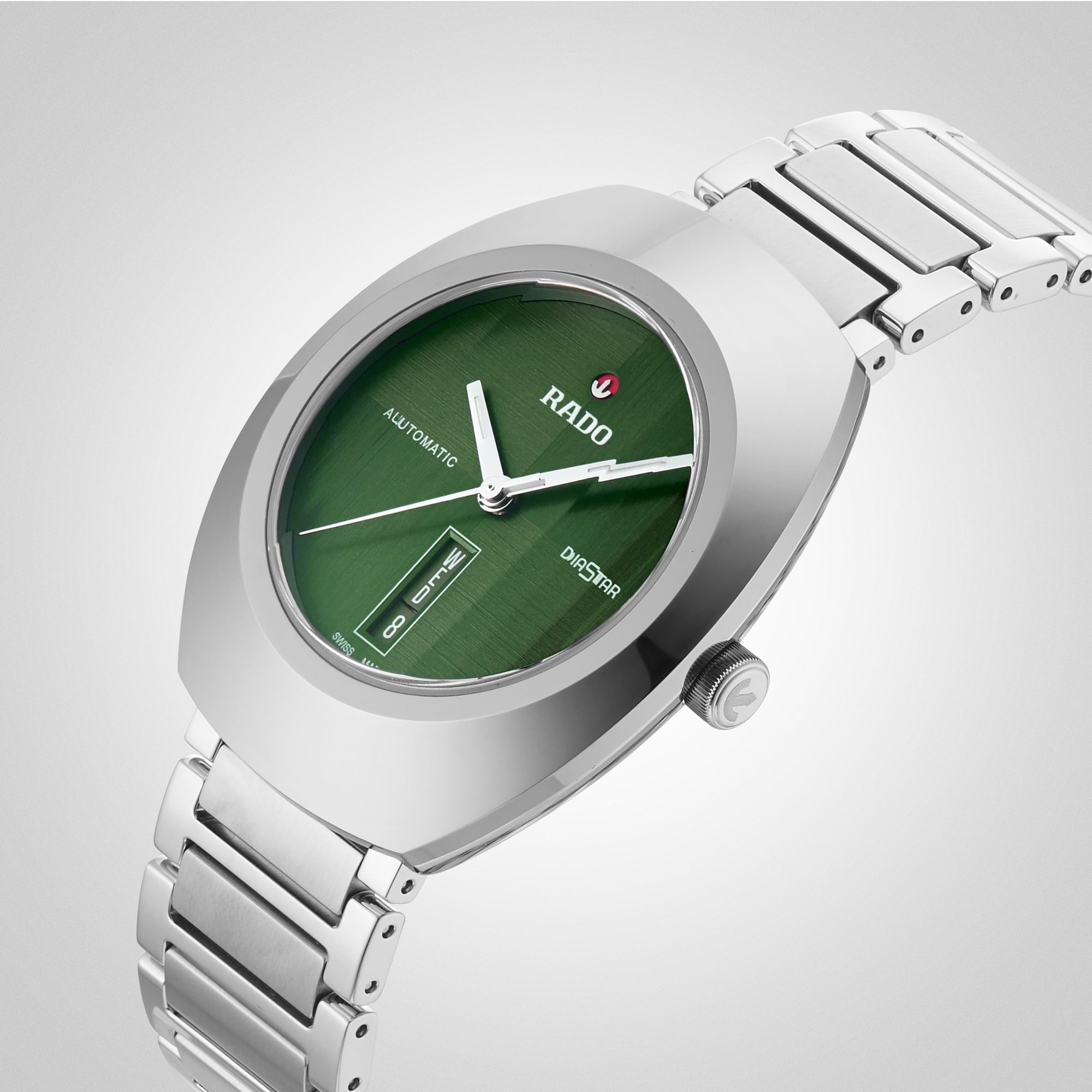 A silver metal wristwatch from Rado DiaStar Original, with a green oval face, sapphire crystal, automatic movement, and date-day display on a light gray background.