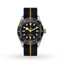 The TUDOR Black Bay 58 features a black dial with gold accents and a black fabric strap with a gold stripe, offering classic diver’s style and precise mechanical movement.