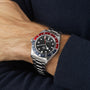 A TUDOR Black Bay GMT wristwatch with a black dial and red-blue bezel is worn on a person’s left wrist, paired with a dark long-sleeve shirt—a classic choice for diving watch enthusiasts.