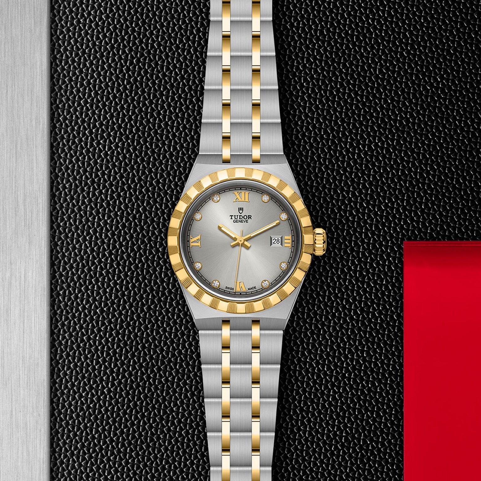 The TUDOR Royal wristwatch features a silver and gold two-tone band, integrated bracelet, silver dial, gold bezel, and diamond hour markers—showcasing sporty elegance and luxury against a textured black backdrop.