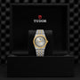 A TUDOR Royal automatic watch with a stainless steel and gold bracelet is showcased in an open black box, displaying the TUDOR logo on the inside lid.