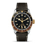 The TUDOR Black Bay GMT S&G features a black and gold bezel, black dial with yellow gold hour markers and hands, date at 3 oclock, and a sleek black leather strap—honoring classic TUDOR diver’s watch heritage.