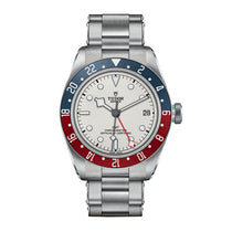 The TUDOR Black Bay GMT is a stainless steel watch featuring an opaline dial, red and blue bezel, GMT function, date at 3 o’clock, and a stainless steel bracelet.