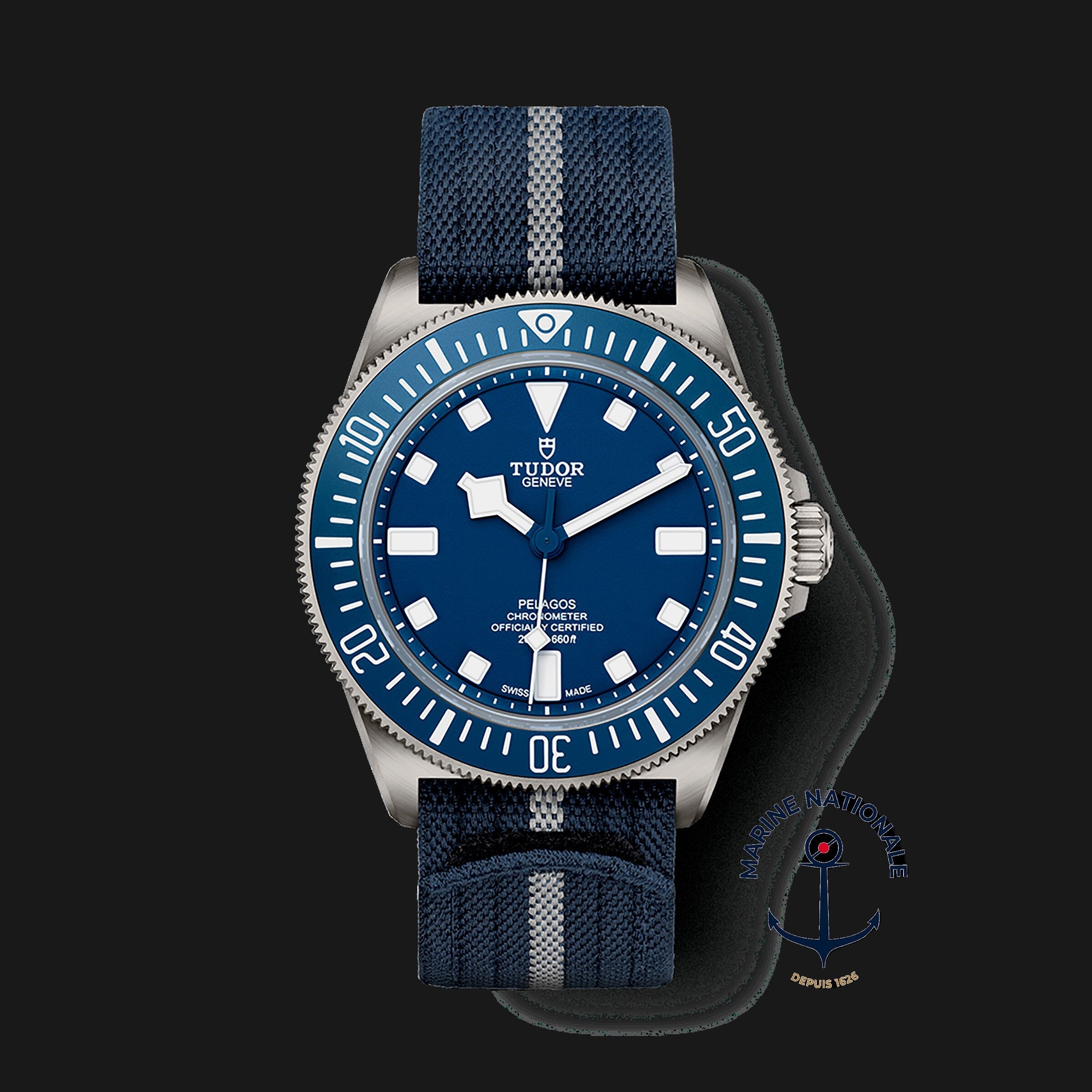 The TUDOR Pelagos FXD features a blue dial and bezel, a blue fabric strap with grey stripe, and a Marine Nationale emblem—making it a distinctive modern diver’s watch.